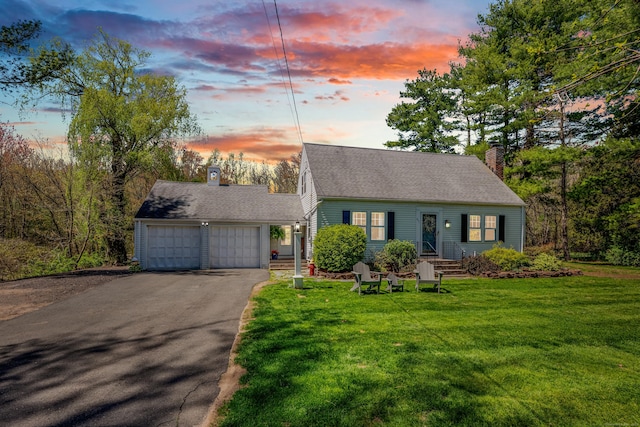 cape cod home featuring a garage, a chimney, driveway, and a front yard