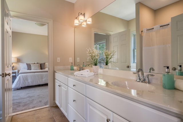 ensuite bathroom with connected bathroom, double vanity, a sink, and tile patterned flooring