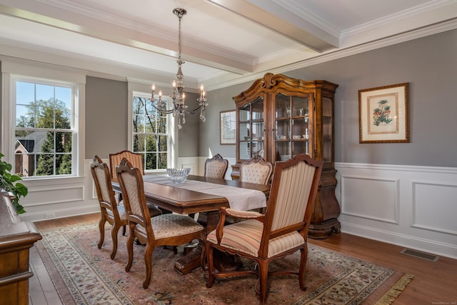 dining area with visible vents, wainscoting, wood finished floors, an inviting chandelier, and ornamental molding