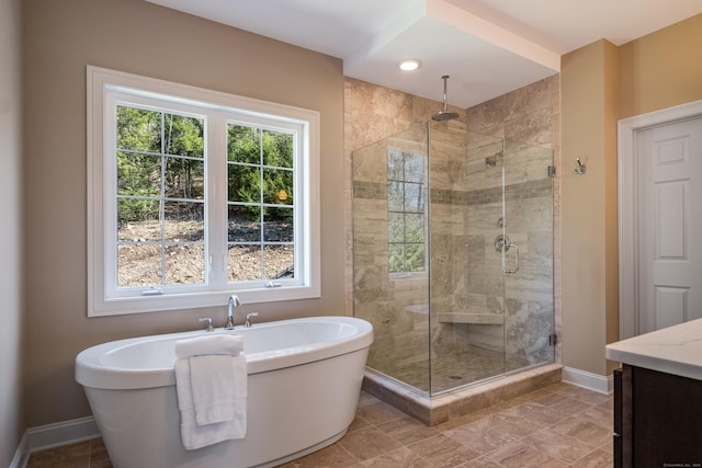 full bath with baseboards, a freestanding tub, vanity, and a shower stall