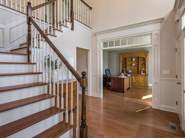 stairs featuring baseboards, a high ceiling, visible vents, and wood finished floors
