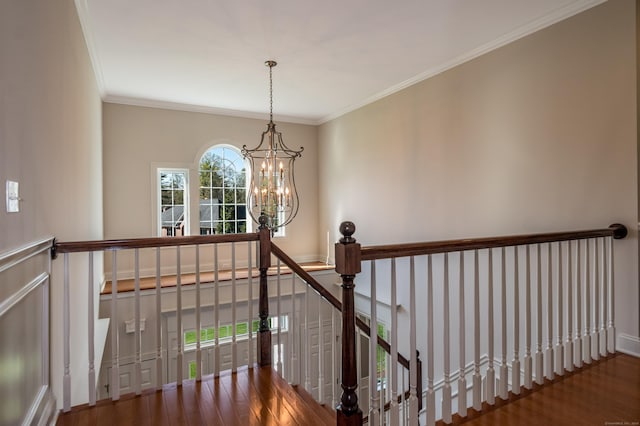 stairway with ornamental molding, wood finished floors, and a chandelier