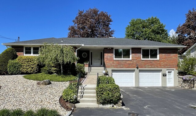 view of front facade featuring driveway, a garage, and brick siding