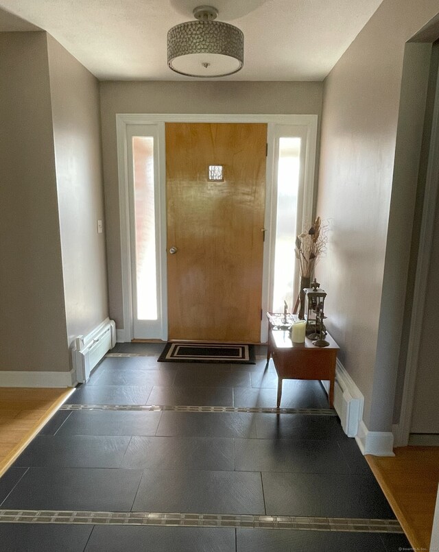 foyer entrance featuring baseboards and a baseboard heating unit