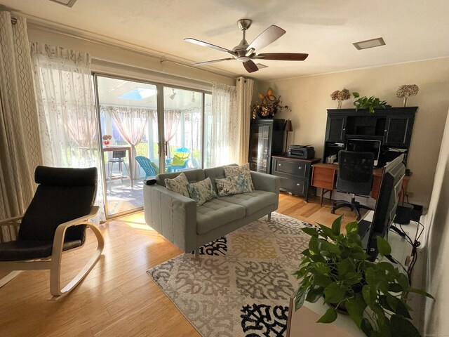living area featuring a ceiling fan, light wood-style floors, and a desk