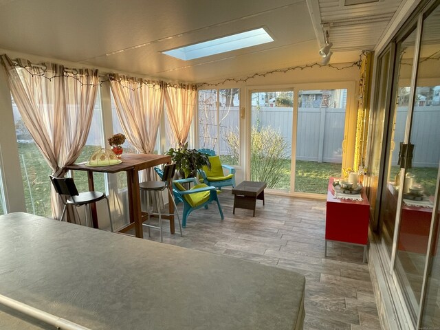 sunroom with a skylight, wood finished floors, and rail lighting