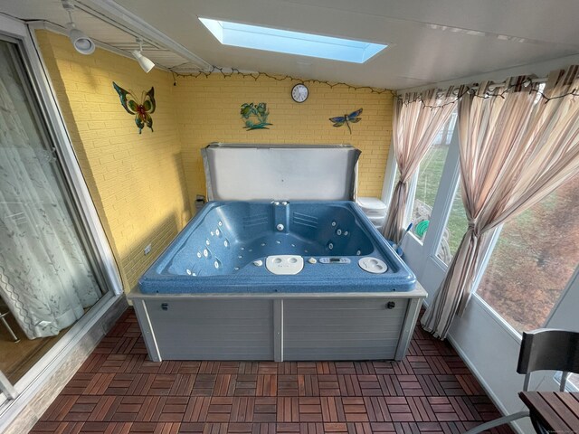 sunroom featuring a skylight, a hot tub, and lofted ceiling