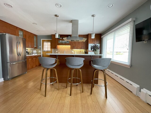 kitchen featuring freestanding refrigerator, island exhaust hood, light wood-style floors, decorative backsplash, and recessed lighting