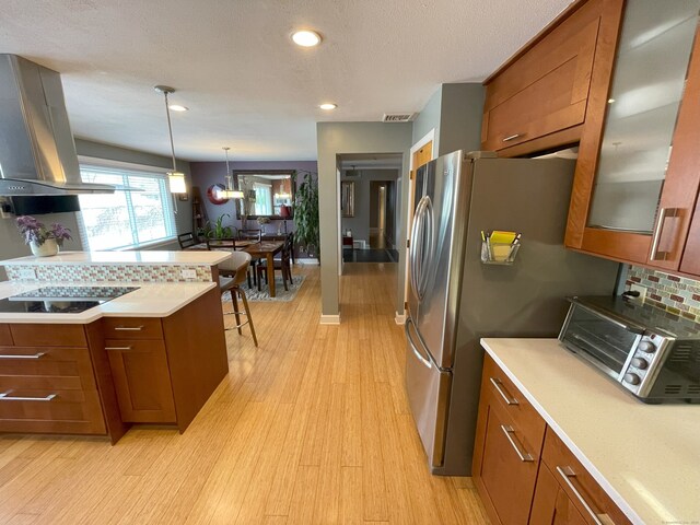 kitchen with brown cabinets, island range hood, light countertops, glass insert cabinets, and light wood finished floors