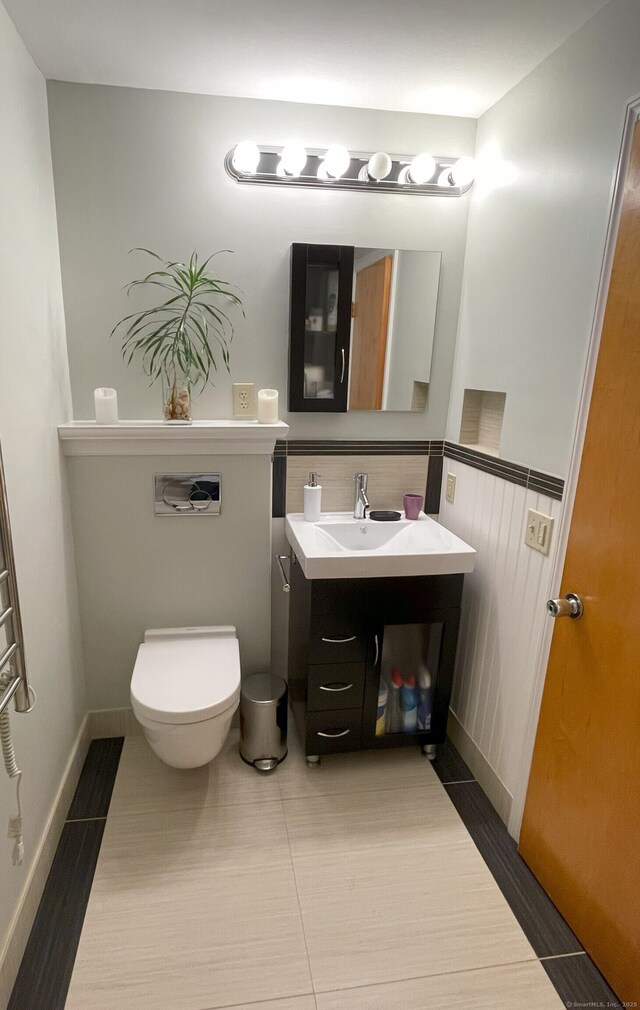 bathroom featuring toilet, vanity, a wainscoted wall, and tile patterned floors