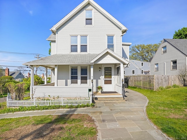 view of front facade featuring fence, a shingled roof, and a front yard