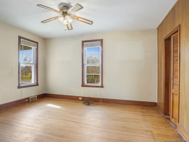 empty room featuring a ceiling fan, baseboards, visible vents, and light wood-style floors