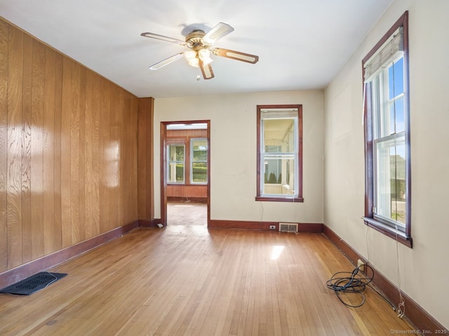 unfurnished room with baseboards, plenty of natural light, hardwood / wood-style floors, and visible vents
