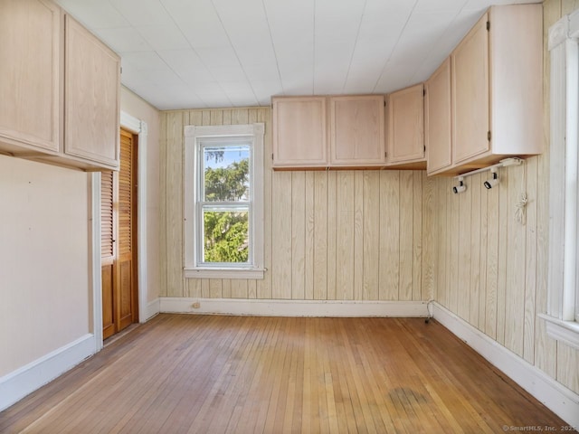 interior space featuring wooden walls, baseboards, and light wood finished floors