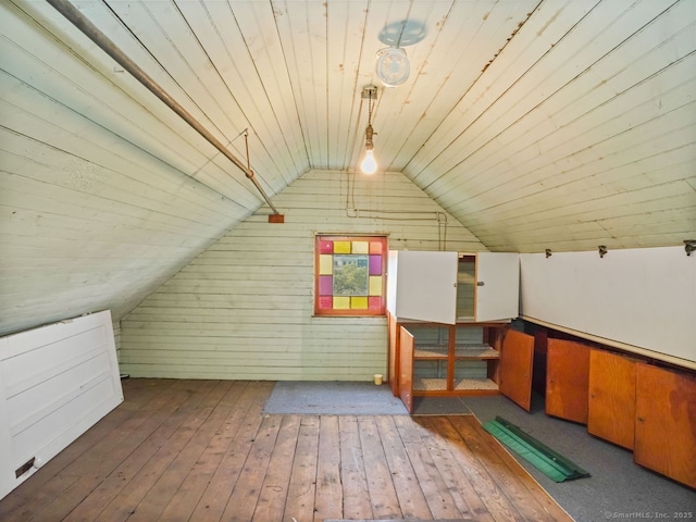 additional living space with wood-type flooring, wood walls, vaulted ceiling, and wooden ceiling