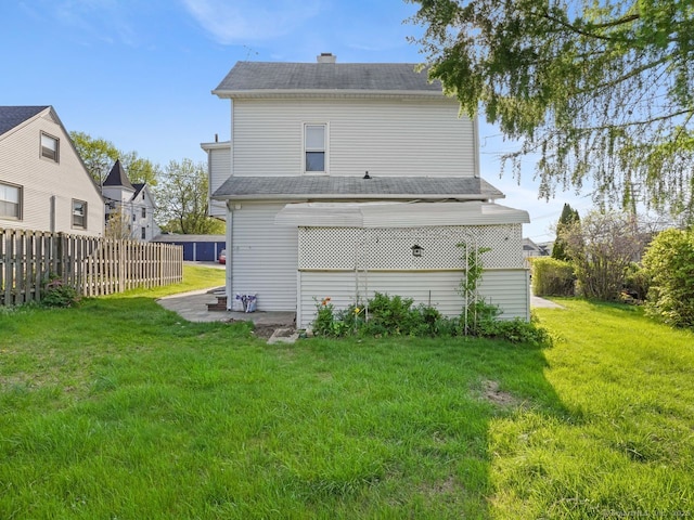 back of property featuring fence, a chimney, and a yard