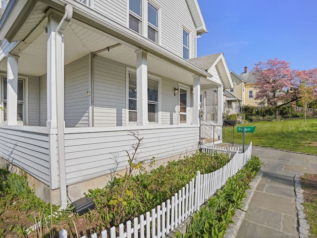 view of home's exterior featuring covered porch, a yard, and fence