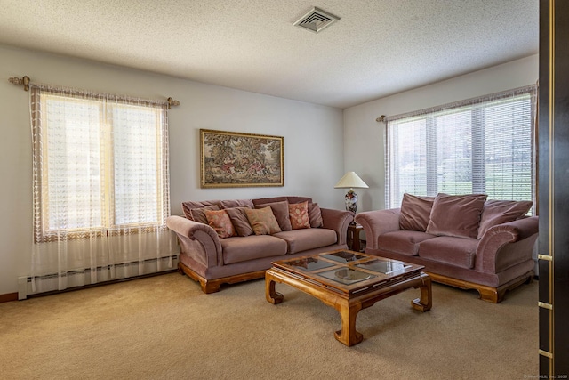 carpeted living room featuring visible vents, a healthy amount of sunlight, a textured ceiling, and a baseboard radiator