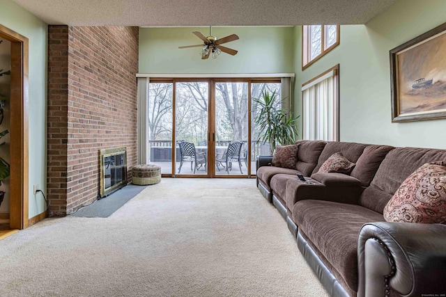 carpeted living room with ceiling fan, a textured ceiling, a fireplace, and a towering ceiling