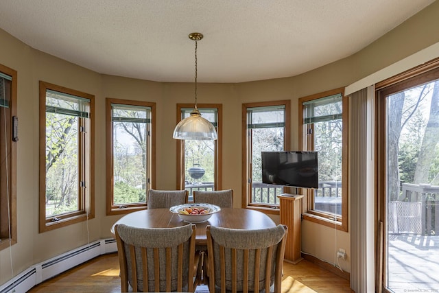 dining space featuring a wealth of natural light, a baseboard heating unit, and a textured ceiling