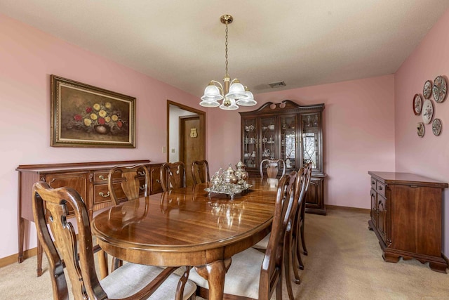 dining space featuring light colored carpet, visible vents, a chandelier, and baseboards
