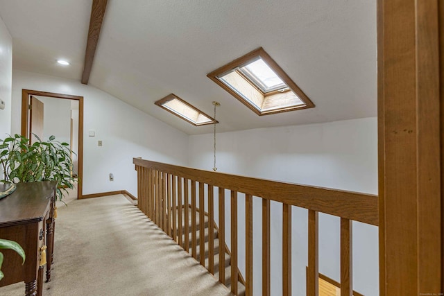 hallway featuring recessed lighting, vaulted ceiling with skylight, light colored carpet, and baseboards