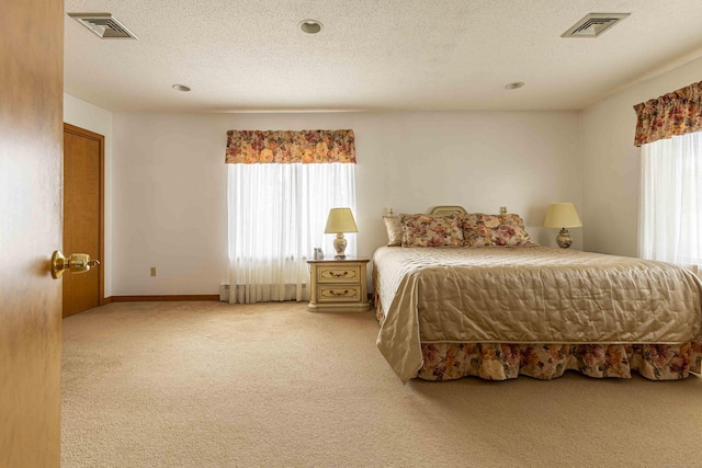 bedroom featuring visible vents, carpet floors, and a textured ceiling