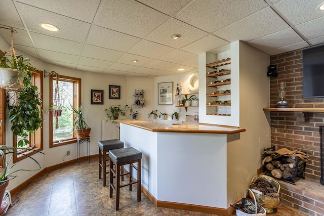 bar featuring baseboards, recessed lighting, indoor wet bar, and a drop ceiling