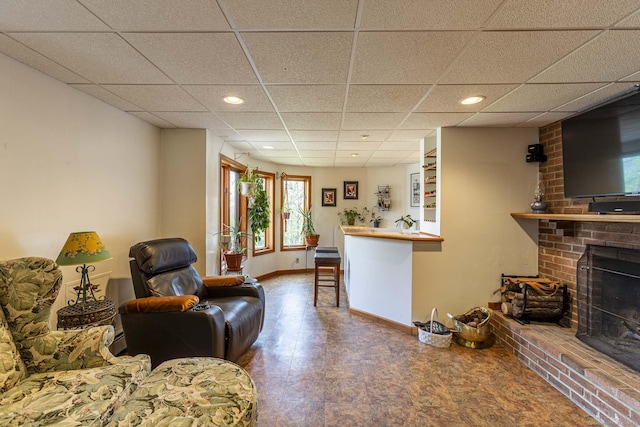 living area with a brick fireplace, recessed lighting, a paneled ceiling, and baseboards