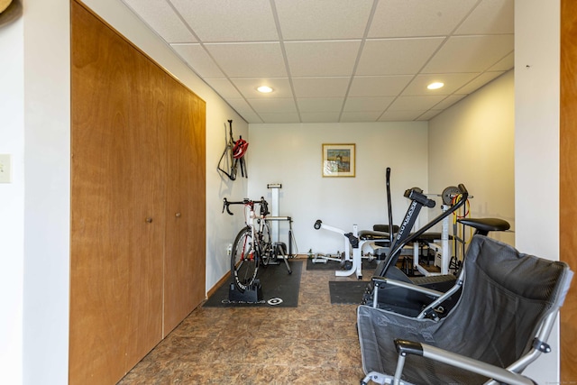 exercise room featuring baseboards, recessed lighting, and a paneled ceiling