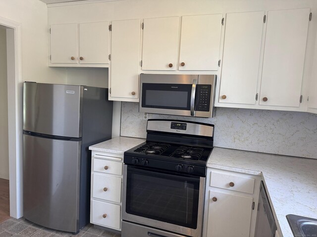 kitchen with tasteful backsplash, stainless steel appliances, white cabinets, and light countertops