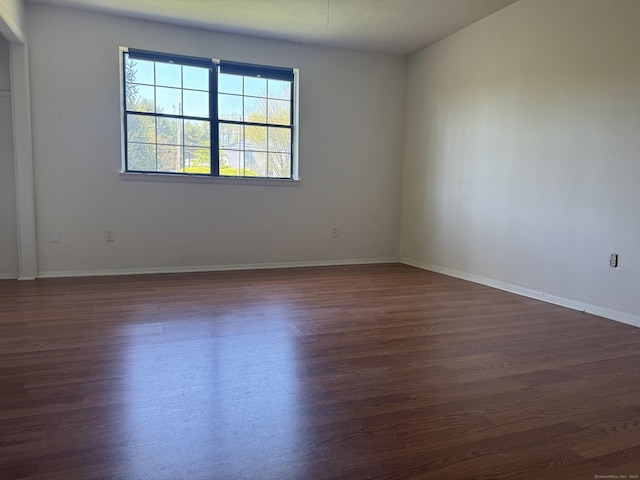 empty room featuring dark wood finished floors and baseboards