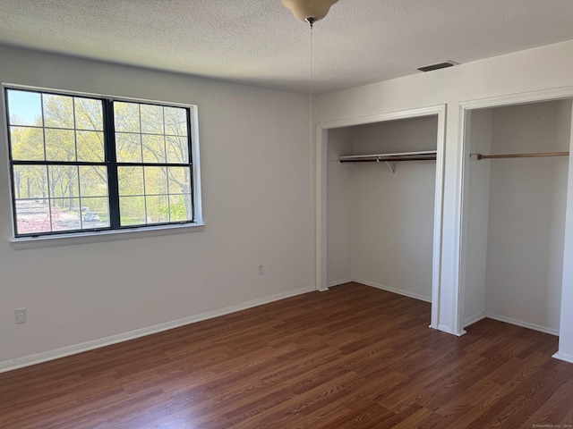 unfurnished bedroom with baseboards, visible vents, wood finished floors, and a textured ceiling