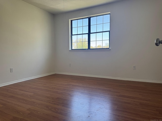 unfurnished room with dark wood-style floors and baseboards