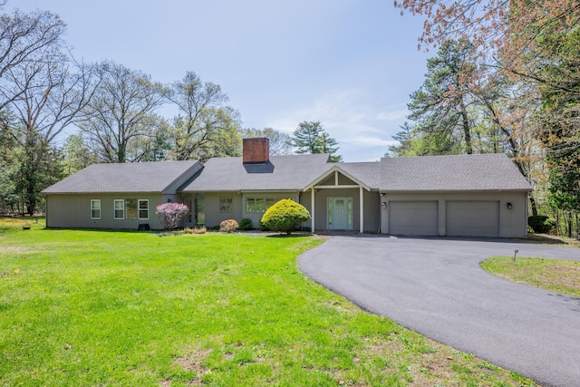 ranch-style house with a garage, a chimney, a front yard, and aphalt driveway