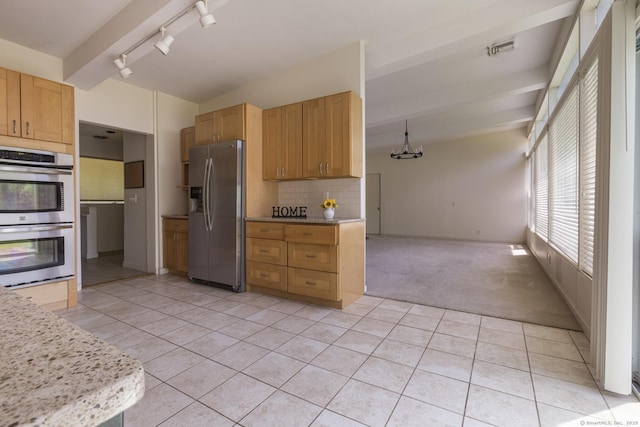 kitchen featuring light colored carpet, appliances with stainless steel finishes, track lighting, light tile patterned floors, and tasteful backsplash