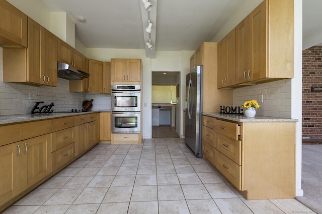 kitchen featuring decorative backsplash, appliances with stainless steel finishes, light stone countertops, light tile patterned floors, and under cabinet range hood