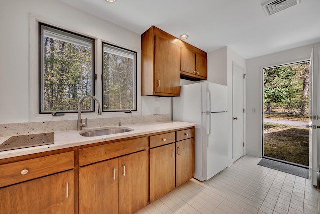 kitchen featuring freestanding refrigerator, visible vents, a wealth of natural light, and a sink