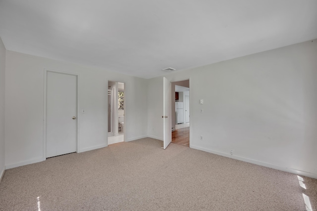 empty room with baseboards, light carpet, and visible vents