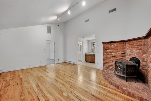unfurnished living room with visible vents, a baseboard radiator, and light wood-type flooring
