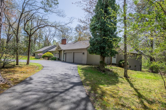 exterior space with a garage, a front lawn, aphalt driveway, and a chimney