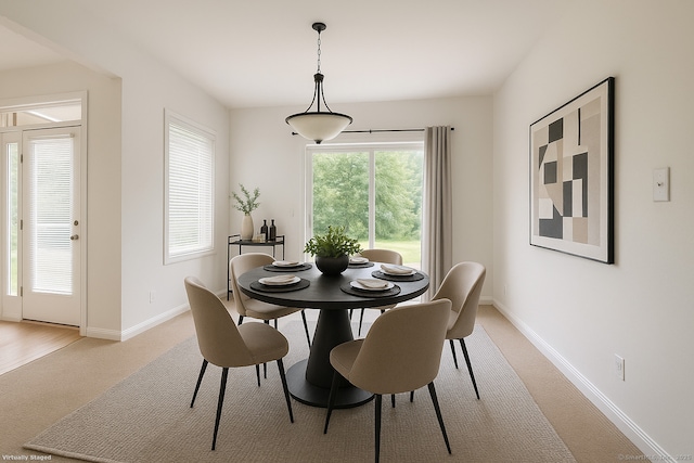 dining space featuring baseboards and light carpet
