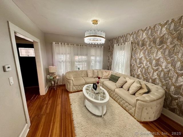 living room featuring baseboards, an inviting chandelier, a wealth of natural light, and wood finished floors