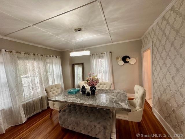 dining area featuring crown molding, dark wood finished floors, a healthy amount of sunlight, and wallpapered walls