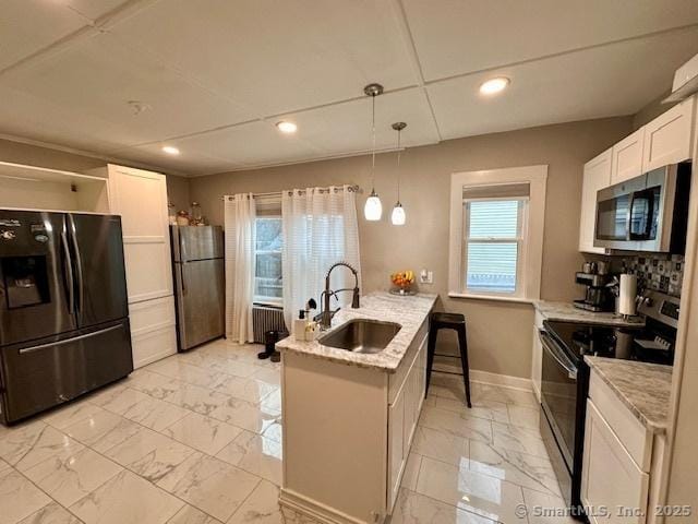 kitchen featuring marble finish floor, radiator, recessed lighting, a sink, and black appliances