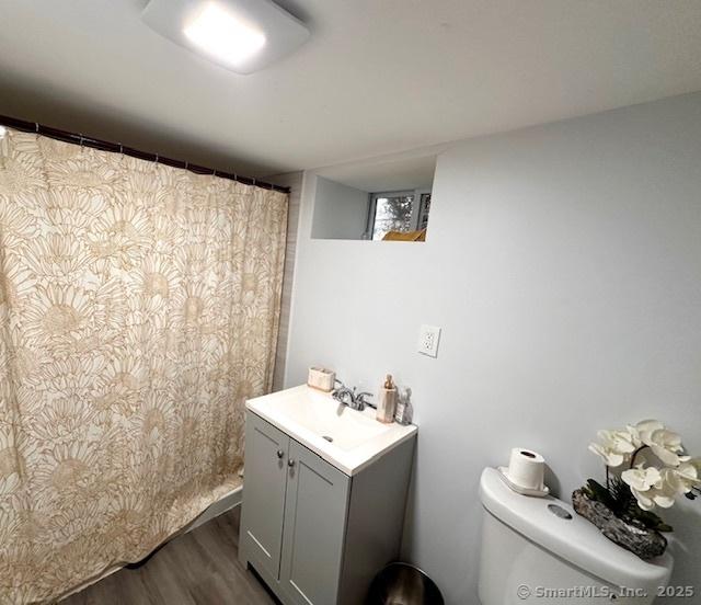 full bath featuring vanity, curtained shower, toilet, and wood finished floors