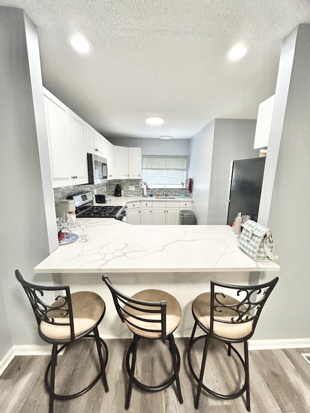 3409 Whitney Ave Apt 24, Hamden, CT 06518 - kitchen featuring stainless steel appliances, a sink, a peninsula, baseboards, and light wood-style flooring