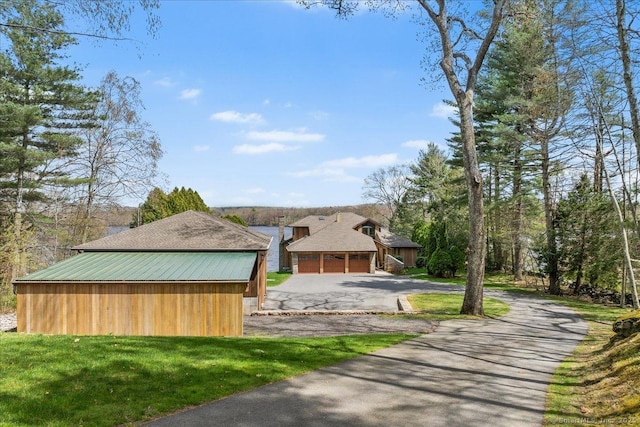 exterior space featuring a garage, aphalt driveway, and a yard