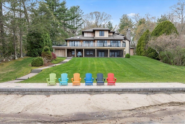 view of front facade featuring a front lawn, a patio area, a balcony, and a chimney