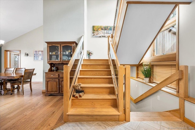 stairway featuring wood finished floors and high vaulted ceiling